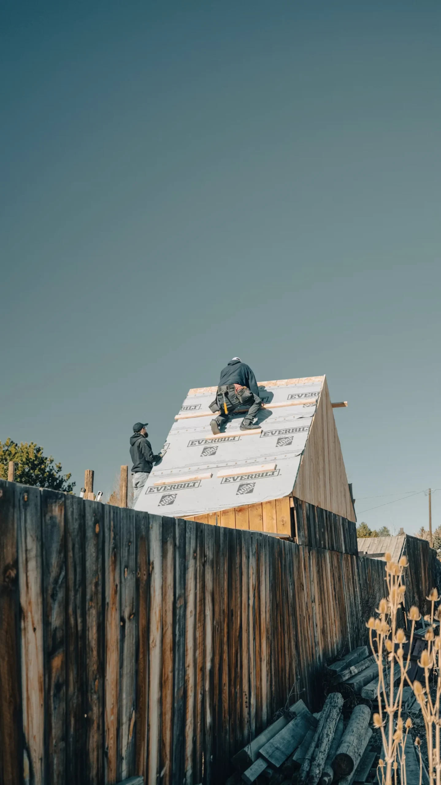 Roofing workers installing a roof under a clear sky
